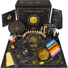 the contents of an astrological kit on a black table with gold foil and other items