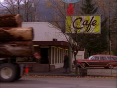 an old car is parked in front of a cafe with a sign that says cafe