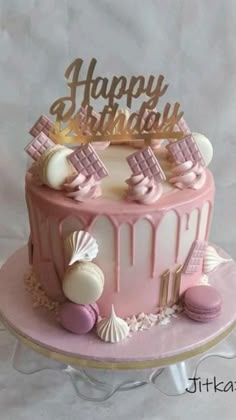 a pink and white birthday cake sitting on top of a table