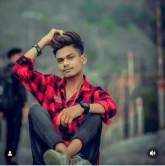 a man sitting on top of a skateboard wearing a red and black checkered shirt