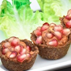 two cupcakes with pomegranate toppings are on a plate next to lettuce