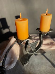 two candles sitting on top of a metal table