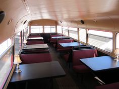 the inside of a school bus with tables and chairs on each side of the seats