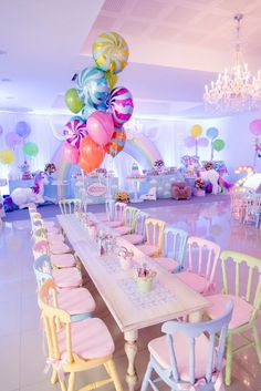 a table with many balloons on it in a room filled with chairs and other decorations