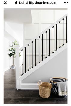 a white staircase with black railings and baskets on the floor