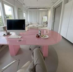 a pink desk in the middle of a living room with a computer monitor and keyboard on it