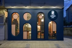 a blue building with round windows on the front and side of it, at night