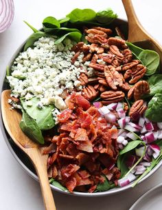 a salad with spinach, bacon, cheese and lettuce in a bowl