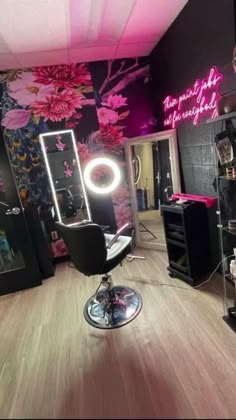 the salon has pink flowers on the wall and black chairs in front of it with neon lights