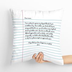 a person holding up a pillow with writing on it