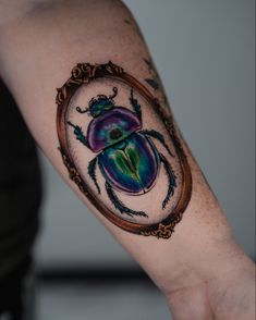 a beetle tattoo on the right arm and shoulder, with an oval frame around it