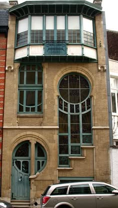 a car is parked in front of a building with arched windows on the side of it