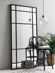 a mirror sitting on top of a table next to a chair and potted plant