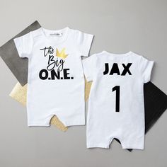 two white onesuits with black and gold numbers on them, one is for the baby