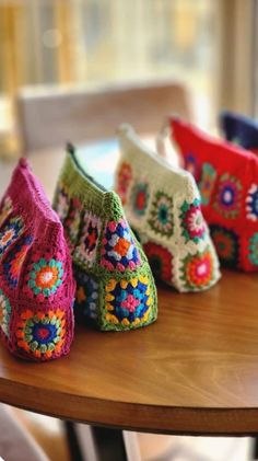 four crocheted purses sitting on top of a wooden table