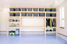 a man standing in front of a shelf filled with lots of storage bins and boxes