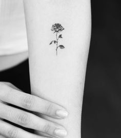 a woman's arm with a rose tattoo on the left side of her arm