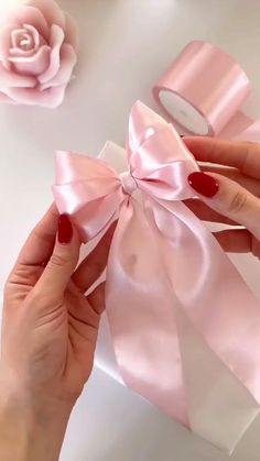 a woman's hands holding a pink ribbon with a rose in the back ground