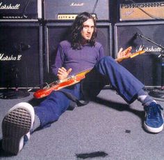 a man sitting on the floor with an electric guitar in front of some amps