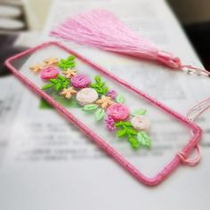 two pink necklaces with flowers on them sitting on top of a piece of paper