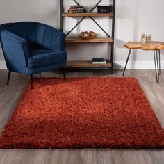 a living room with a blue chair and red rug on the floor in front of a bookshelf