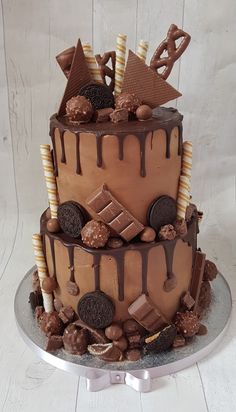 a three layer chocolate cake with cookies and candy on top