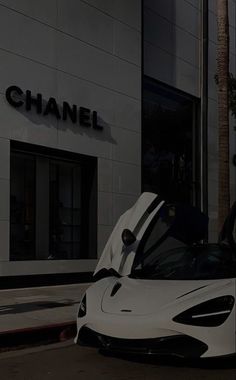 a white sports car parked in front of a chanel store with its doors open