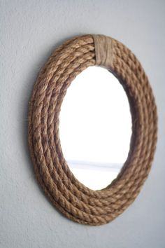 a rope hanging on the wall with a round mirror in it's center,