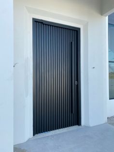 a large black door on the side of a white building