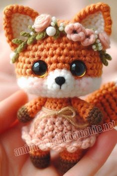 a small crocheted fox with flowers on it's head sitting in someones hand