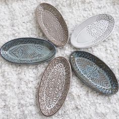 five decorative plates sitting on top of a white carpet