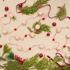 christmas decorations are laid out on a white tablecloth with red and white ribbons around them