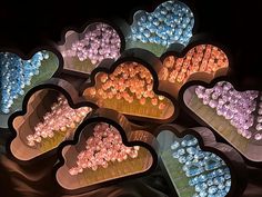 several heart shaped trays filled with candies on a black surface, some in the shape of hearts