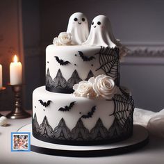 a wedding cake decorated with white roses and black lace, topped with two ghost figurines