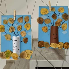 two paper bags with leaves on them are hanging from clothes pegs and one has a cardboard tree