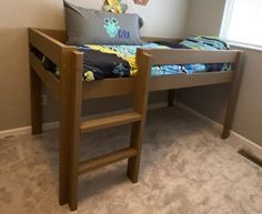 a wooden bed frame in a bedroom with a ladder to the bottom and a pillow on top