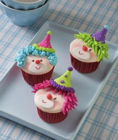 three cupcakes decorated with clown faces on a plate