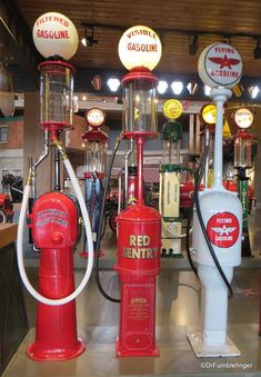 several red and white fire hydrants in a room with gas pumps on the floor