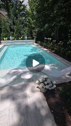 an outdoor swimming pool surrounded by trees and shrubs, with the water running down it's sides