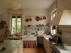 a kitchen with many pots and pans hanging on the wall above the stove top