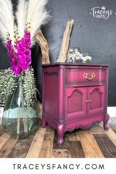 two vases with flowers and branches in them sitting on a wooden floor next to a chalkboard wall