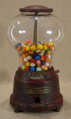 an old fashioned gummy machine with lots of colorful balls in it's top