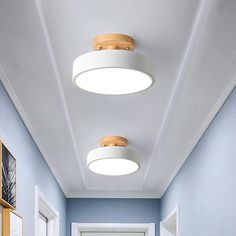 a hallway with blue walls and two round lights hanging from the ceiling, along with pictures on the wall