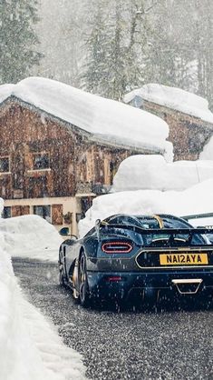 a black sports car parked on the side of a road in front of snow covered houses