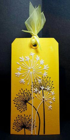 a yellow tag with dandelions on it and a bow hanging from the top