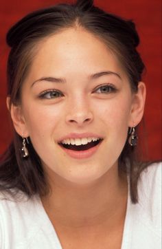 a young woman is smiling for the camera with her hair in a bun and earrings