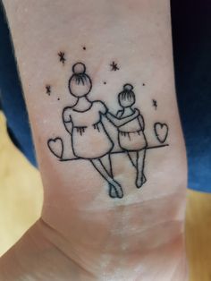 a small tattoo on the wrist of a woman with two girls holding each other's hands