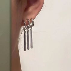 a pair of silver earrings hanging from the back of a woman's ear