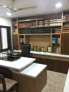 an office with many bookshelves and chairs in front of the counter top area