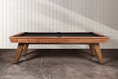 a pool table sitting in front of a white wall with tiles on the walls and floor